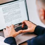 Man typing on laptop at home office, focused on work, illustrating remote work lifestyle.